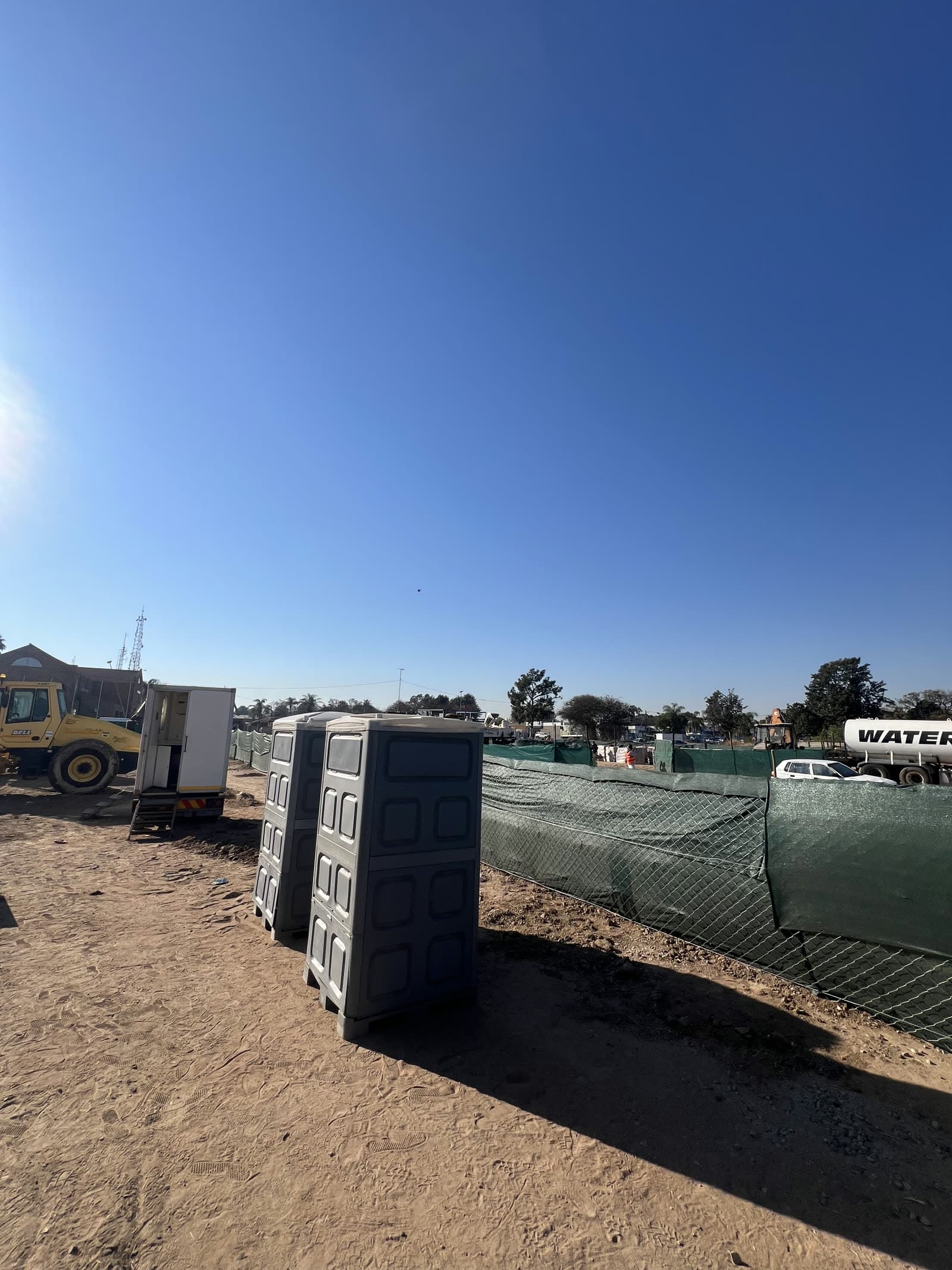 Chemical toilet units placed beside a site office container and earthmoving plant on a construction site in Limpopo